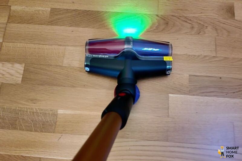 Die neue Bodendüse des Dyson V16 Piston Animal wird im Test gezeigt wie er auf Holzboden saugt und der grüne Laser ist deutlich zu sehen.